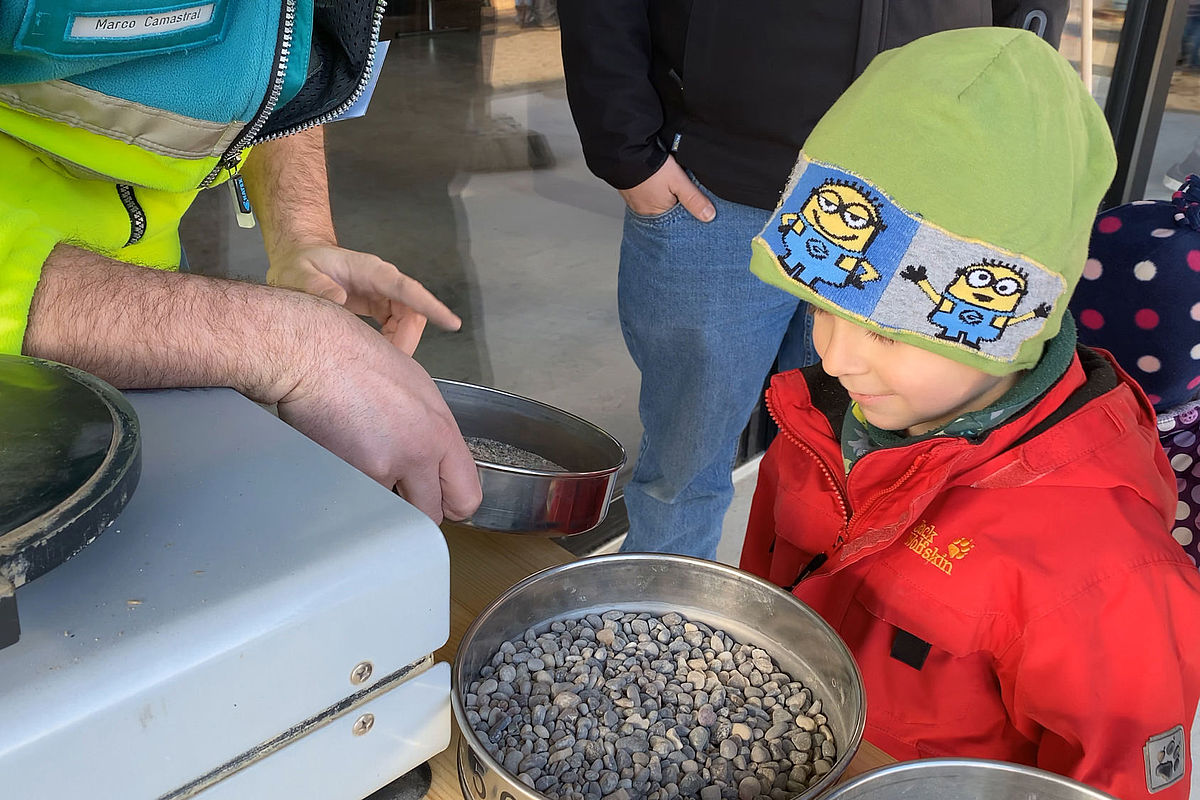 Unser Recyclist erklärt einem Jungen den Prozess vom Sieben des Gesteins