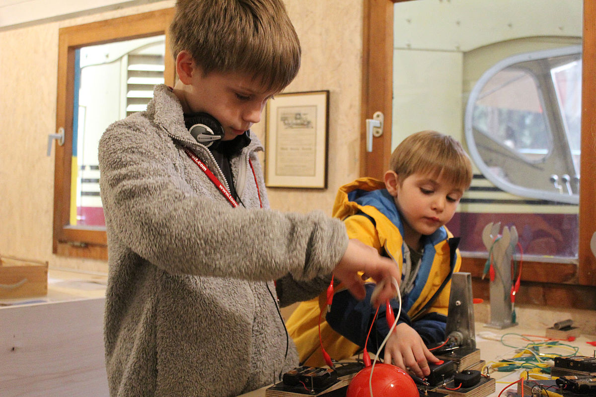 Jungs experimentieren im Bauwagen mit Strom, wer bringt das Lämpchen zuerst zum Leuchten?