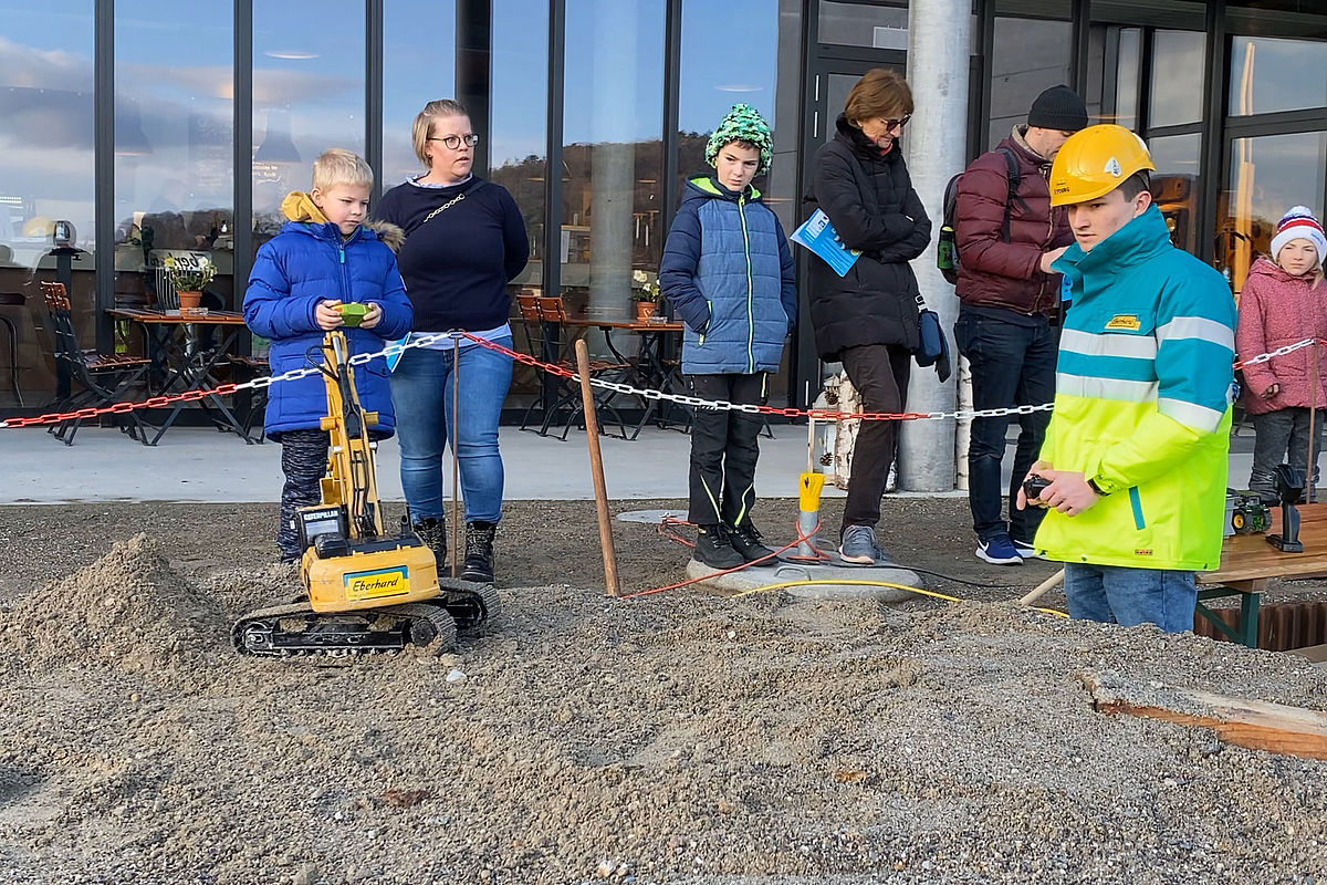 Lernender zeigt den Kindern am ebi.YOUNG Day, wie sie mit den Modellen fahren können