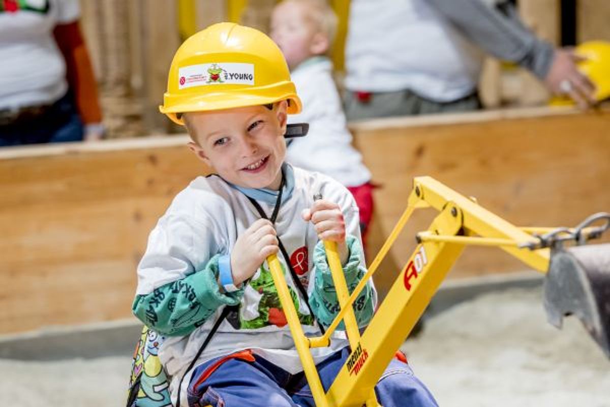 Junge mit Bauhelm hat Spass beim Bäggerle